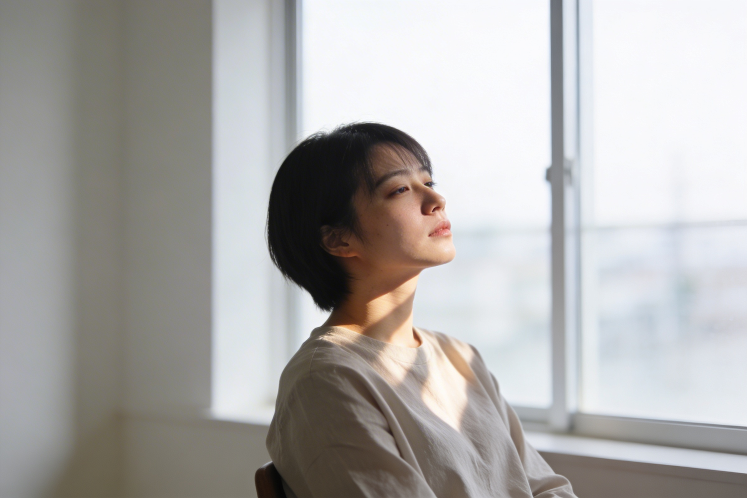 A person sitting quietly by a window in soft daylight